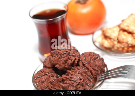 Untertasse mit Pralinen oder Gebäck in der Nähe von Tee auf weißem Hintergrund Stockfoto