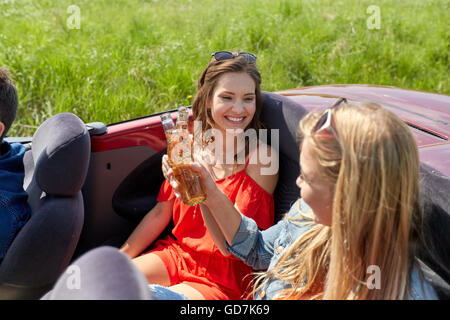 Glückliche Freunde fahren im Cabrio Auto mit Bier Stockfoto