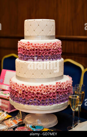 weiße Multi Level Hochzeitstorte mit rosa Blumenschmuck Stockfoto