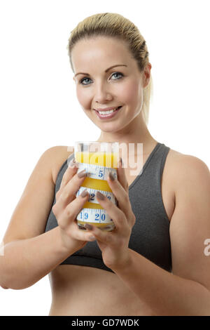 Happy Fitness-Frau hält ein Glas Orangensaft mit einem Maßband um das Glas für eine Konzeptidee zu schmal zu halten Stockfoto