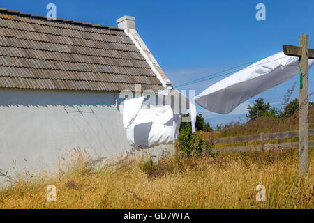 Alte Scheune mit Stücken von Wäsche auf einer Wäscheleine an einem Tag im Sommer durch den Wind geblasen. Stockfoto