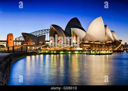 SYDNEY, Australien, 1. Juli 2016 - Sydney Opera House und Harbour Bridge bei Sonnenuntergang reflektierende Beleuchtung Lichter in unscharfen Bucht Stockfoto