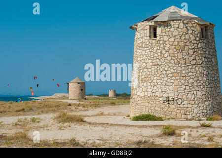 Alte Windmühlen an einem Strand, bevölkert von Windsurfer und Kitesurfer in Lefkada, Lefkas Stockfoto