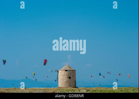 Alte Windmühlen an einem Strand, bevölkert von Windsurfer und Kitesurfer in Lefkada, Lefkas Stockfoto