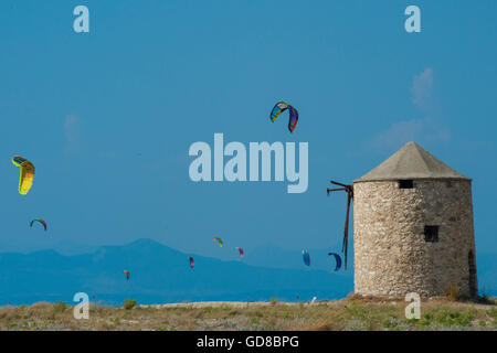 Alte Windmühlen an einem Strand, bevölkert von Windsurfer und Kitesurfer in Lefkada, Lefkas Stockfoto