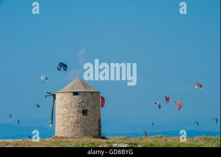 Alte Windmühlen an einem Strand, bevölkert von Windsurfer und Kitesurfer in Lefkada, Lefkas Stockfoto