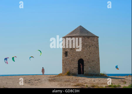 Alte Windmühlen an einem Strand, bevölkert von Windsurfer und Kitesurfer in Lefkada, Lefkas Stockfoto