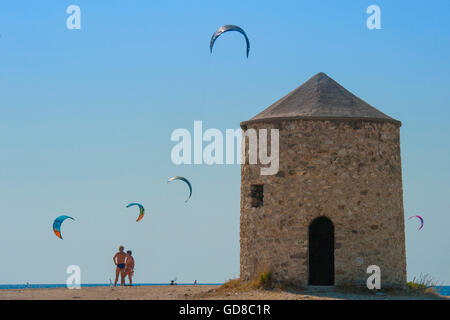 Alte Windmühlen an einem Strand, bevölkert von Windsurfer und Kitesurfer in Lefkada, Lefkas Stockfoto