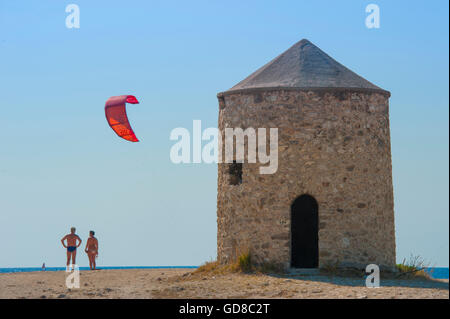 Alte Windmühlen an einem Strand, bevölkert von Windsurfer und Kitesurfer in Lefkada, Lefkas Stockfoto