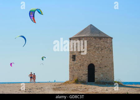 Alte Windmühlen an einem Strand, bevölkert von Windsurfer und Kitesurfer in Lefkada, Lefkas Stockfoto