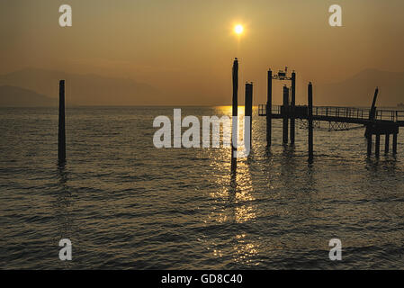 Pier bei Sonnenuntergang auf dem großen See in einem wunderbaren Wettbewerb mit Berge am Horizont Stockfoto