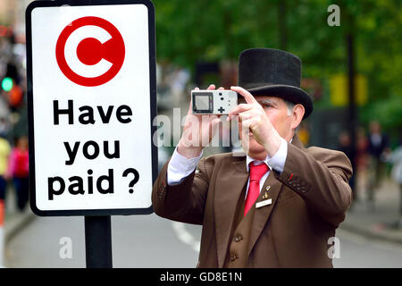 London, England, Vereinigtes Königreich. Hotel-Portier nehmen ein Foto von einer Demonstration in der Park Lane, neben einer City-Maut-Schild Stockfoto