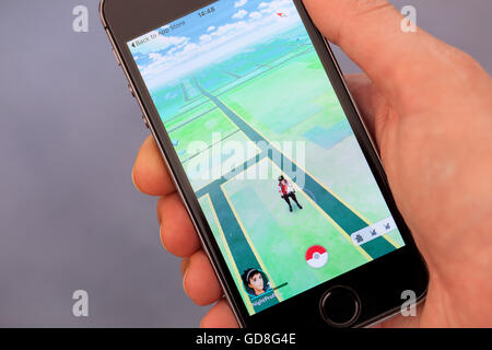 Tambow, Russische Föderation - 13. Juli 2016 Person Hand spielen Pokemon Go-Anwendung auf dem Apple iPhone. Grauen Hintergrund. Stockfoto