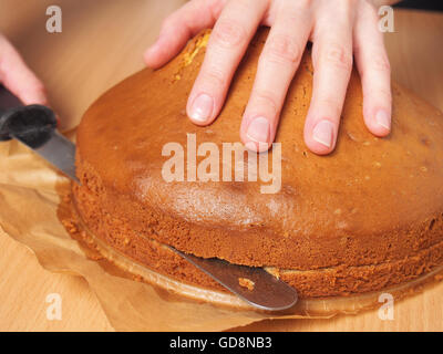 Schneiden Kuchen in Schichten. Torte mit Buttercreme-Füllung und geriebener Schokolade Topping machen. Serie. Stockfoto