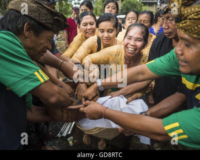 Ubud, Bali, Indonesien. 13. Juli 2016. Menschen greifen durch die Reste von einem Mitglied ihrer Familie während der Masse Feuerbestattung in Ubud. Nachdem die Überreste exhumiert und verbrannt sind gehen Menschen durch die Asche Knochenfragmente, herausgreifen, die dann zum Meer gesendet werden. Menschen vor Ort in Ubud die Überreste von Familienmitgliedern exhumiert und verbrannt ihre Überreste in einer Masse Einäscherung Zeremonie Mittwoch. Fast 100 Menschen werden verbrannt und in die größte Masse Einäscherung in Bali in Jahren diese Woche bestattet. Die meisten Menschen auf Bali sind Hindus. Bildnachweis: ZUMA Press, Inc./Alamy Live-Nachrichten Stockfoto