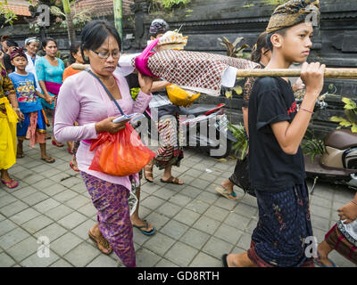 Ubud, Bali, Indonesien. 13. Juli 2016. Eine Frau betet während die Überreste von einem Mitglied ihrer Familie durch die Straßen von Ubud, während die Masse Einäscherung Mittwoch eingenommen werden. Menschen vor Ort in Ubud die Überreste von Familienmitgliedern exhumiert und verbrannt ihre Überreste in einer Masse Einäscherung Zeremonie Mittwoch. Fast 100 Menschen werden verbrannt und in die größte Masse Einäscherung in Bali in Jahren diese Woche bestattet. Die meisten Menschen auf Bali sind Hindus. Bildnachweis: ZUMA Press, Inc./Alamy Live-Nachrichten Stockfoto