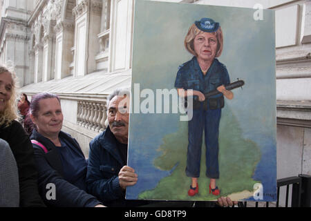 London, UK. 13. Juli 2016. Politischer Künstler Kaya versammelten Mar mit seiner neuesten Malerei auf den Tag, an dem der neue konservative Parteichef Theresa kann MP Premierminister des Vereinigten Königreichs, als Demonstranten und öffentlichen wurde Downing Street am 13. Juli 2016 in London, Vereinigtes Königreich. Dieses Gemälde porträtiert Theresa May als thuggish Polizei Frau hält einen Schlagstock mit einem Nagel durch sie. Politische Satire auf ihrem hardline Umgang mit der Polizei. Bildnachweis: Michael Kemp/Alamy Live-Nachrichten Stockfoto