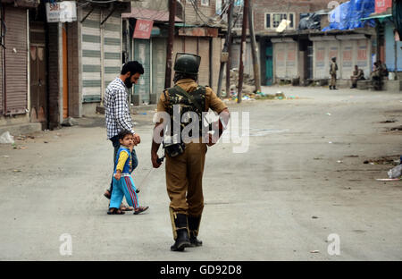 Srinagar, indische verabreicht Kaschmir. 14. Juli 2016. Ein Kaschmir-Kind schauen in Richtung eines indischen Soldaten während der Ausgangssperre nach die Morden an 39 Kaschmir Regierung Kräfte in Humhama am Stadtrand von Srinagar, Indien. Heftige Proteste in Kaschmir über die Ermordung eines jungen Rebellen Kommandanten Burhan Wan hat mindestens 39 Menschen das Leben gekostet und über Touusands verwundet, seit letztem Freitag. Es ist die schlimmste Gewalt im Bereich seit 2010. Bildnachweis: Sofi Suhail/Alamy Live-Nachrichten Stockfoto