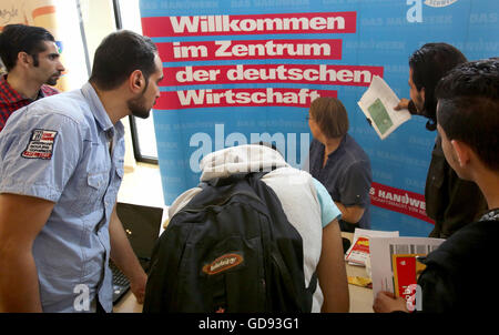 Schwerin, Deutschland. 14. Juli 2016. Leute schauen auf dem Stand von der Handwerkskammer Schwerin ist eine Anzeigetafel, geschrieben mit "Willkommen in der Mitte der deutschen Wirtschaft" auf den ersten Job Ausbildungsmesse für Flüchtlinge bei der Industrie- und Handelskammer in Schwerin, Deutschland, 14. Juli 2016. Mehr als 300 junge Menschen, viele von ihnen aus Syrien und Eritrea, besuchten die Messe. Foto: BERND WUESTNECK/Dpa/Alamy Live News Stockfoto