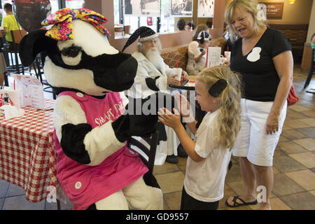 Duluth, GA, USA. 12. Juli 2016. Ein junger Kunde spielt mit petite Chick-Fil-A-Kuh "Molly" im Restaurant auf der Kette "Kuh Appreciation Day" © Robin Rayne Nelson/ZUMA Draht/Alamy Live News Stockfoto