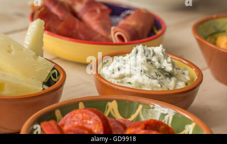 Tapas, Tzatziki, Manchego, Chorizo und Schinken auf einem weißen Tisch Stockfoto