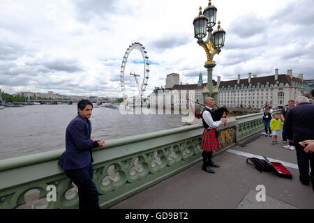 Eine Piper auf Westminster Bridge mit dem London Eye ein Londoner Wahrzeichen im Hintergrund. Stockfoto