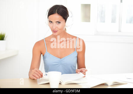 Ziemlich hispanic Frau sitzt in ihrem Zimmer und anhören von Musik über Kopfhörer Stockfoto