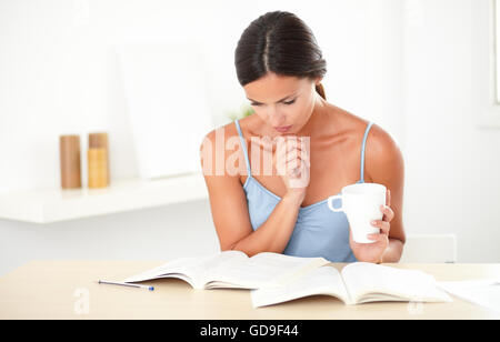 Stilvolle Frau im blauen t-Shirt Denken während des Studiums ihre Bücher zu Hause Stockfoto