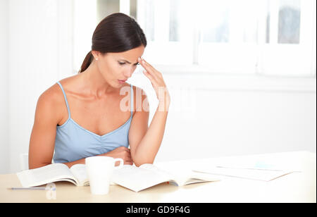 Hübsche Frau im stilvollen Bluse Konzentration beim Lesen Bücher bei indoor - Exemplar Stockfoto