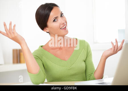 Glücklich Latin Lady in elegantes Hemd sitzt und mit ihrem Laptop zu Hause beim Betrachten Sie Stockfoto