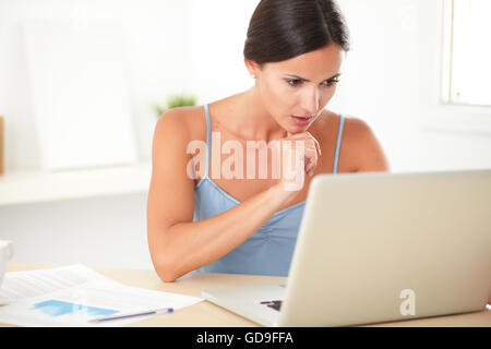 Schöne Frau, die Konzentration auf ihre Arbeit in den Computer während der Sitzung in das Haus an der Rezeption Stockfoto