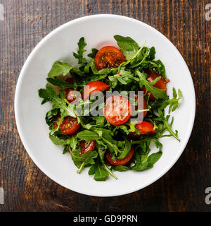 Salat mit Cherry-Tomaten und Rucola in Schüssel auf hölzernen Hintergrund weiß Stockfoto