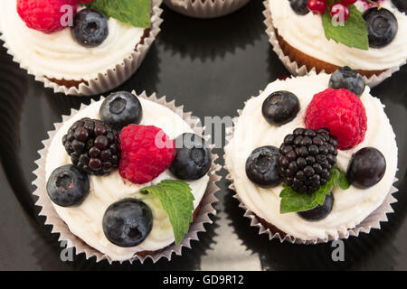 Elegante Cupcakes mit Beeren auf der schwarzen Platte. Stockfoto