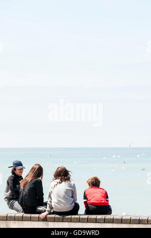 Menschen sitzen an Wand in Margate direkt am Meer. Stockfoto