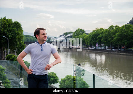 Foto des jungen Mannes in der Nähe des Flusses an europäische grüne Stadt. Hübscher Kerl Outdoor portrait Stockfoto