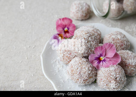 Hausgemachte Erdbeer, Datum, Cashew und Kokosnuss Glückseligkeit Ball mit essbaren Blüten Stockfoto
