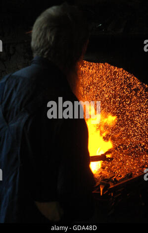 Schmied vor seiner Schmiede wo Funken aus der Kohle steigen. Stockfoto