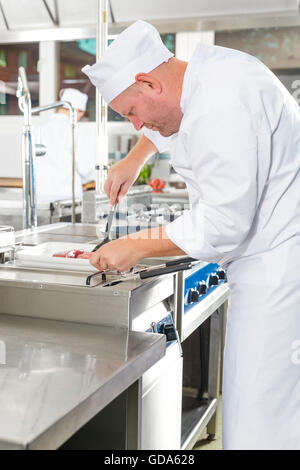 Fokussierte Chefkoch Rindersteak in Pfanne in der Küche Stockfoto
