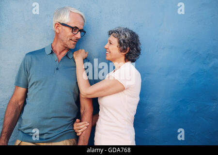 Porträt von liebevollen reifer Mann und Frau einander betrachten. Romantisch zu zweit stehen vor einer blauen Wand zusammen. Stockfoto