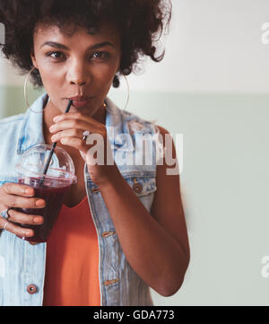 Nahaufnahme Bild von einer attraktiven jungen Frau Saft zu trinken. Stilvolle afrikanische weibliche Modell immer eine Erfrischung. Stockfoto