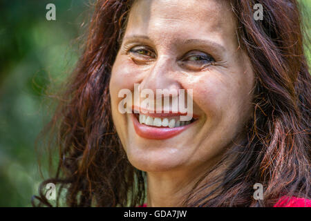 Porträt von lächelnd und glücklich Reife Frau mit lange gewellte rötlich braunen Haaren, roten Lippenstift Stockfoto
