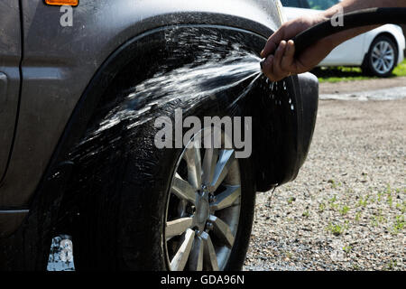 junger Mann sorgfältig sauber waschen seine Lieblings-Auto-Rad Stockfoto