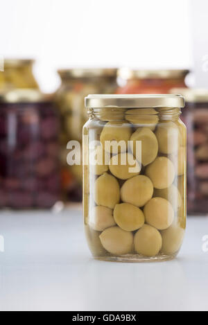 Eingelegte grüne Oliven Glas mit anderen Gurken Gläser im Hintergrund Stockfoto