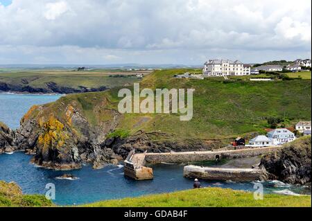 Mullion Cove Cornwall England UK. Ein Künstler sitzen am unteren Rand der Szene malen die Ansicht. Stockfoto