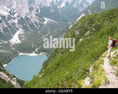 Italien, Trentino-Alto Adige, Provincia di Bolzano, Wandern auf einem schmalen Pfad über dem Pragser Wildsee, Herrsteingipfel Blick auf die Pragser Wildsee mit Wanderer Stockfoto