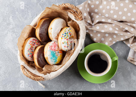 Bunte Donuts und Kaffeetasse am Steintisch. Ansicht von oben Stockfoto