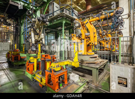 Konkurs und verlassene Automobilfabrik. Gelbe Roboter Schweißen Autos in einer Produktionslinie Stockfoto