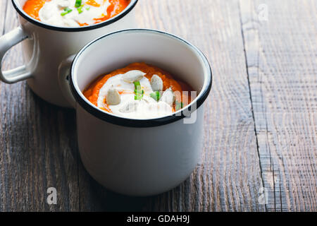 Hausgemachte Winter-Kürbis-Suppe in weiße Tasse auf rustikalen Holztisch Stockfoto