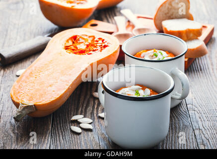 Hausgemachte Winter-Kürbis-Suppe in weiße Tasse auf rustikalen Holztisch Stockfoto