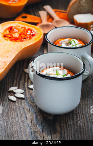 Hausgemachte Winter-Kürbis-Suppe in weiße Tasse auf rustikalen Holztisch Stockfoto